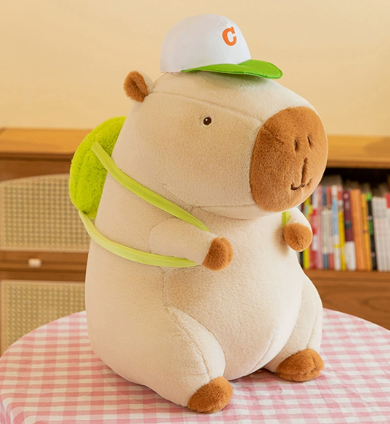 Front view of the CapyCuddle capybara plush with cap and backpack