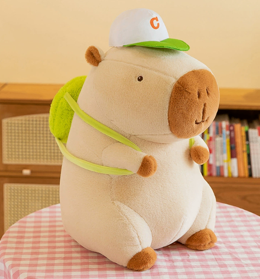 CapyCuddle capybara plush in cream with green cap and green backpack